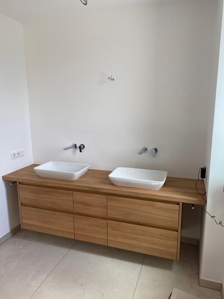 Doppelwaschtisch mit zwei weißen Waschbecken auf einem Holzunterbau in einem modernen Badezimmer.
