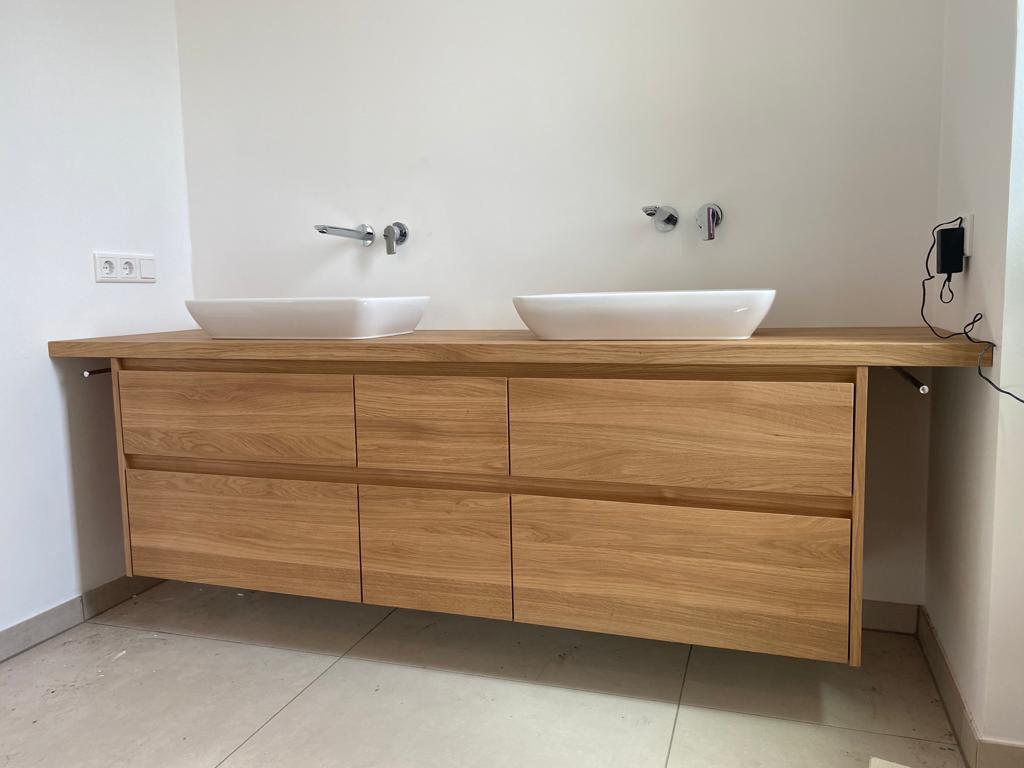 Holzwaschtisch mit zwei weißen Waschbecken und modernen Wasserhähnen in einem Badezimmer.